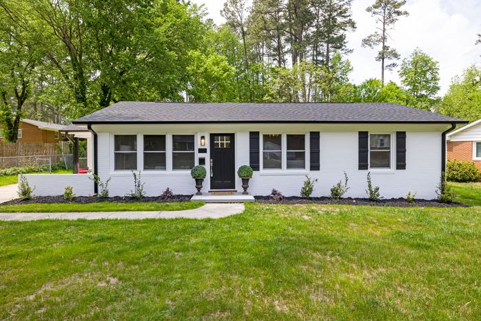 Single-story painted brick ranch with black shutters