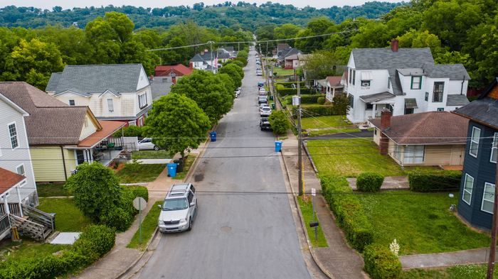 Residential street of older frame houses below wooded hills